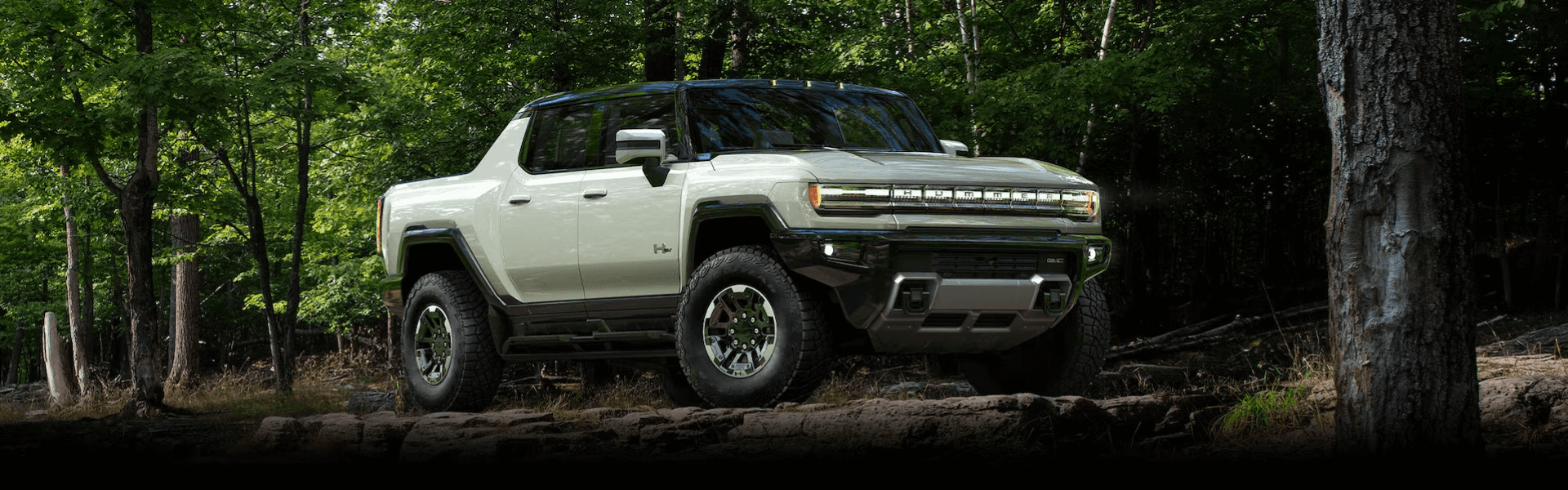 2024 GMC Hummer EV Pickup Truck Driving In A Forest Banner
