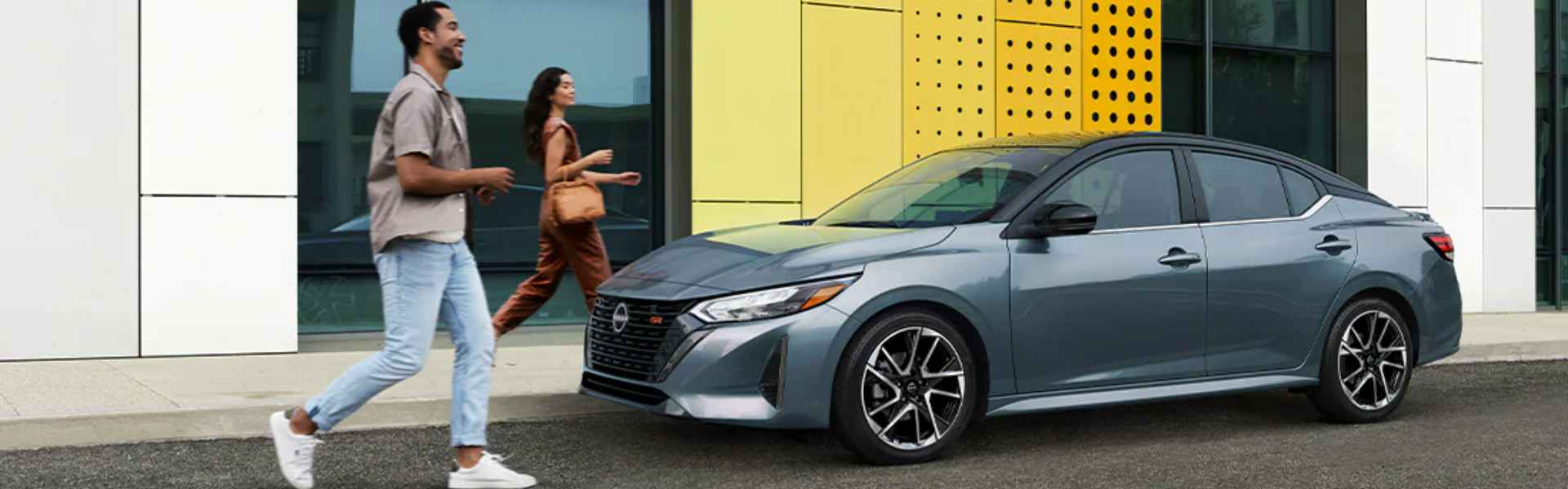 2024 Nissan Sentra parked on a street with a vibrant Banner