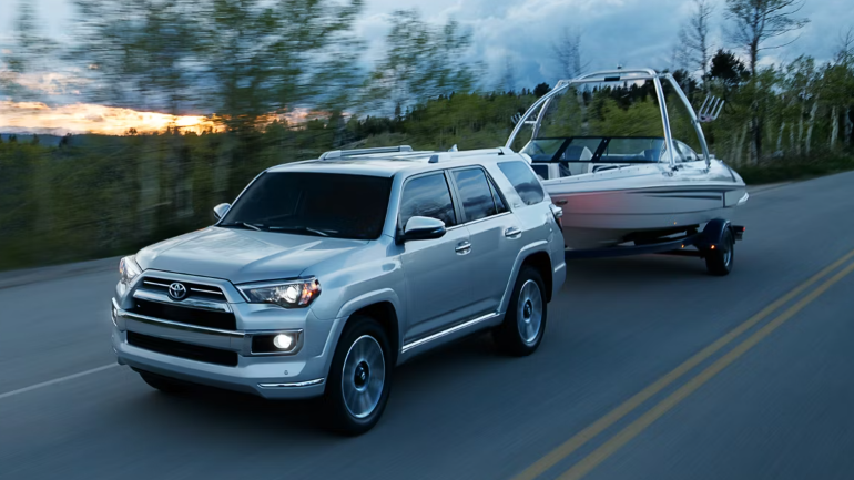 2024 Toyota 4Runner towing a boat along a road surrounded by a serene-Features