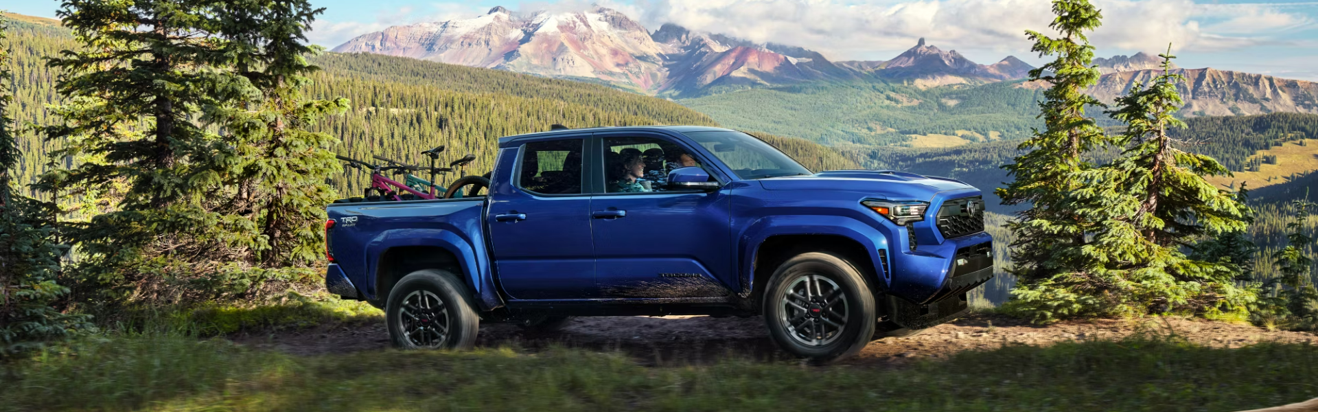 2024 Toyota Tacoma driving through a scenic mountainous terrain-Banner