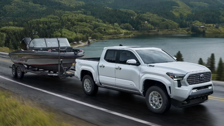 2024 Toyota Tacoma towing a boat on a scenic road beside a lake and lush green hills-Features