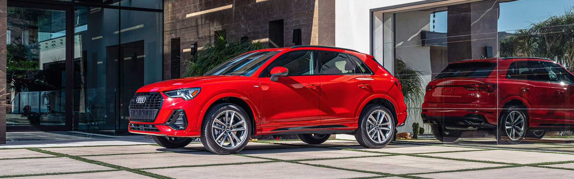 2025 Audi Q3 parked in front of a modern glass-walled building-Banner