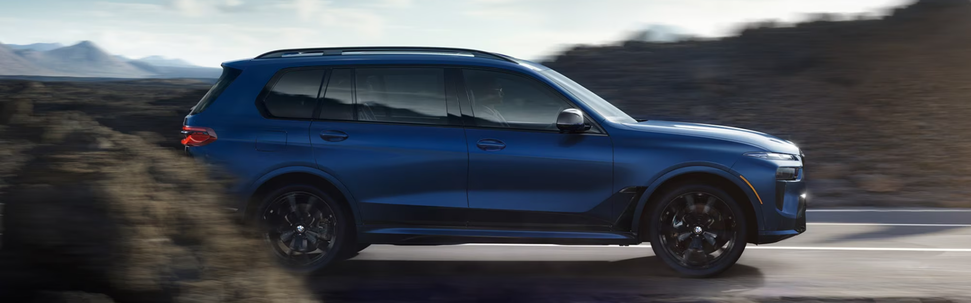 2025 BMW X7 is blue running with side view-Banner