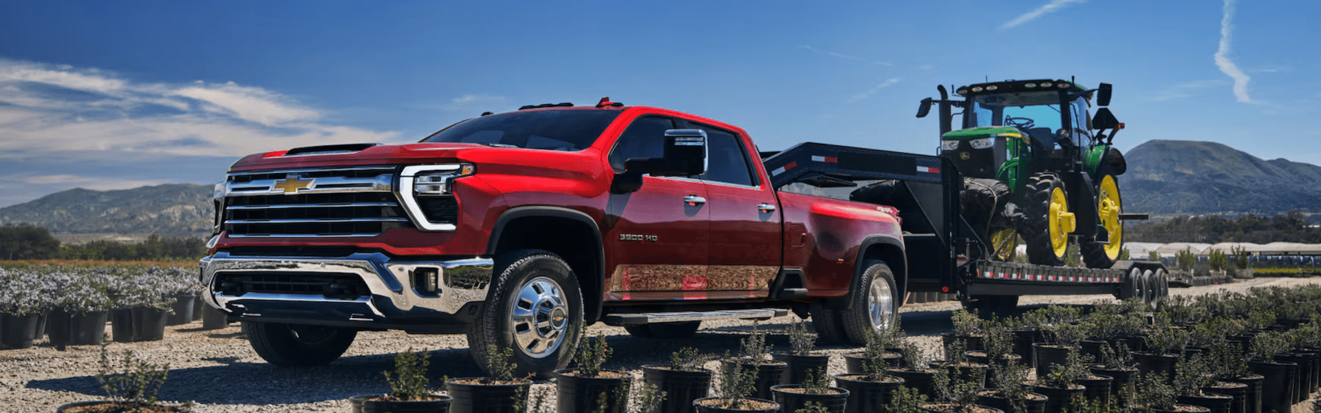 2025 Chevrolet Silverado 3500 HD towing a large piece of farming equipment on a trailer