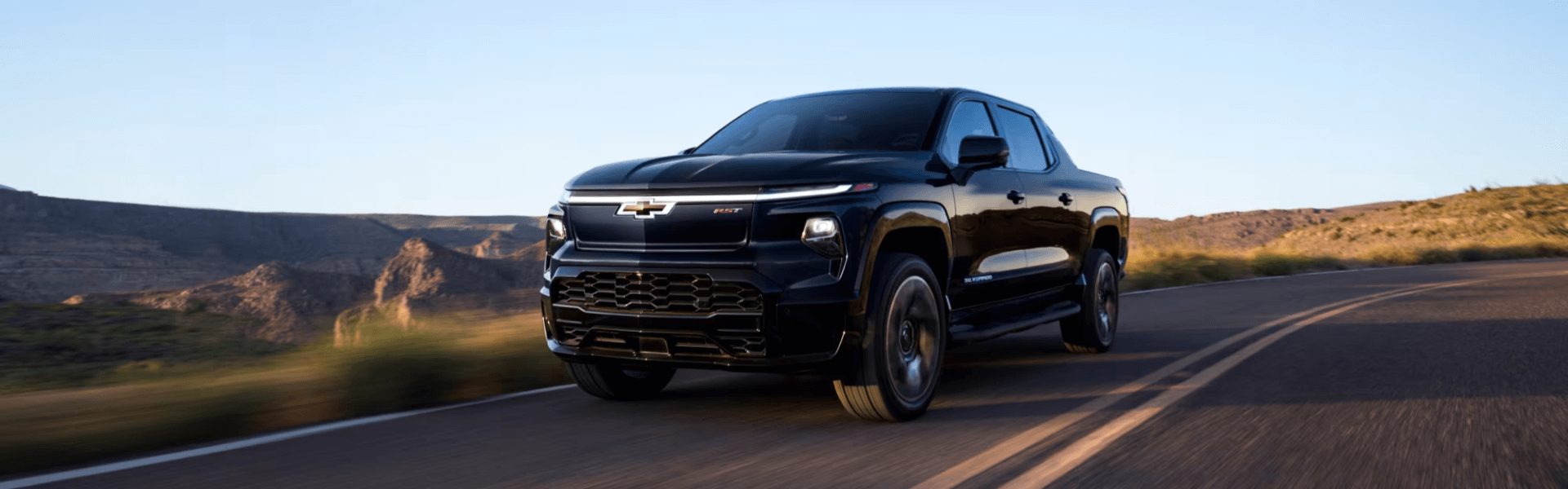 2025 Chevrolet Silverado EV In Black Three Quarters View Going Down The Road Banner