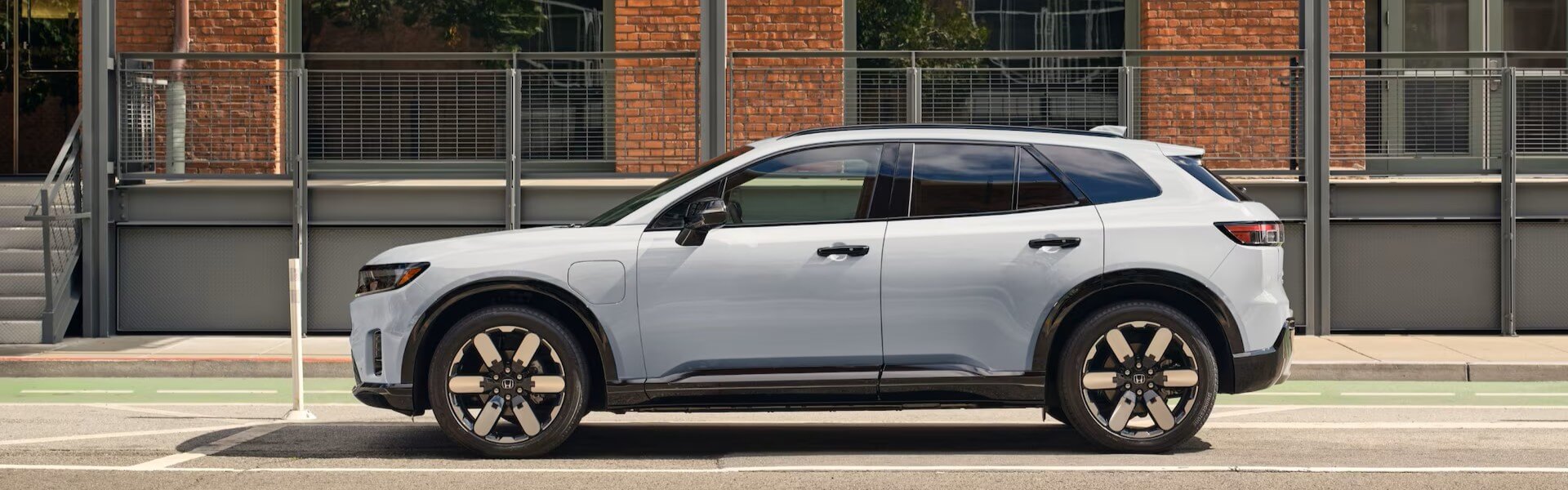 2025 Honda Prologue Banner - All-electric SUV with a sophisticated, contemporary design parked in front of a brick building