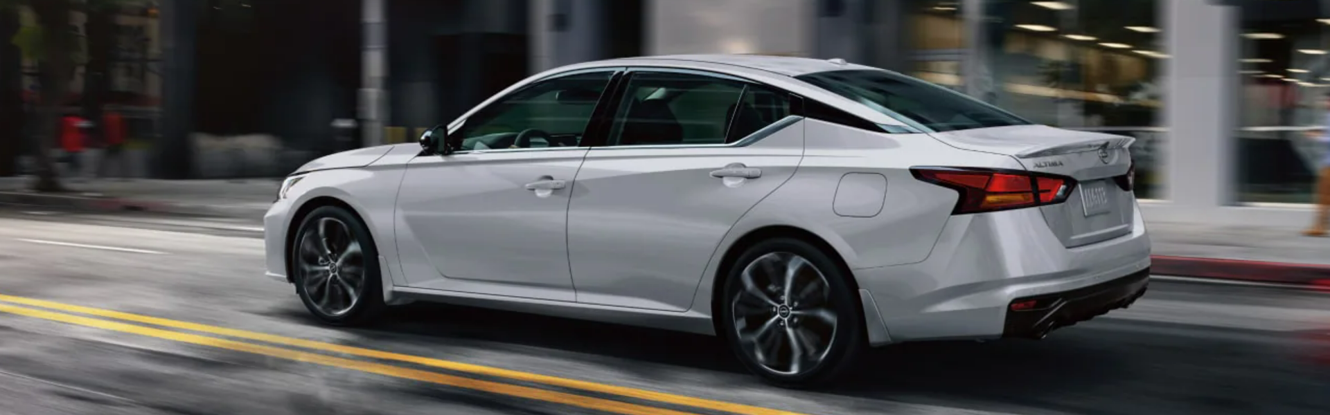 2025 Nissan Altima driving on a city street-Banner