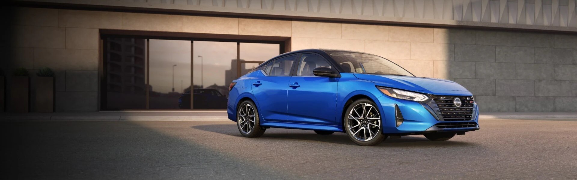 2025 Nissan Sentra In Blue Parked In A Driveway In Front Of A Building Banner