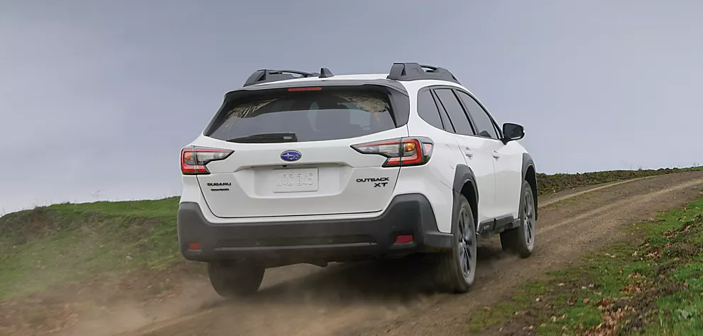 2025 Subaru Outback driving uphill on a dirt road