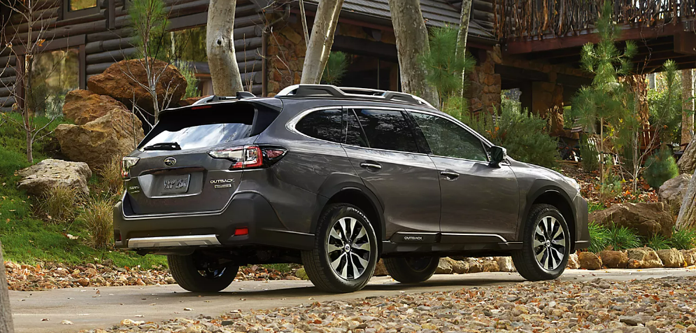 2025 Subaru Outback parked in a natural, wooded environment near what appears to be a cabin