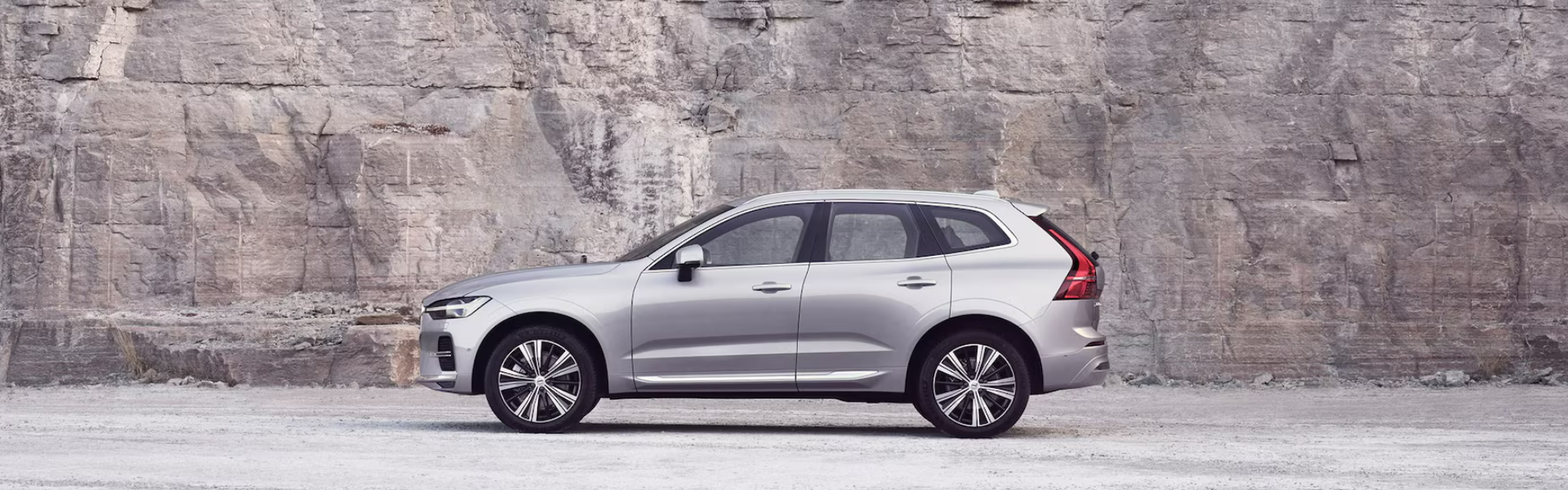 2025 Volvo XC60 parked in front of a rocky cliff BANNER