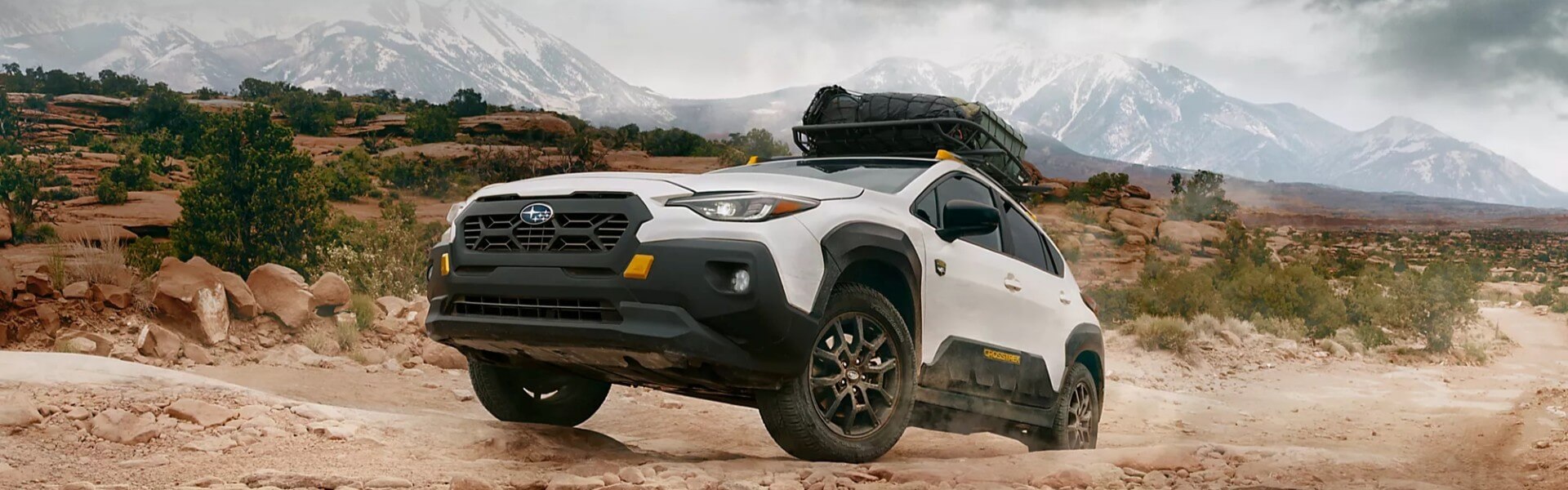 2026 Subaru Crosstrek Wilderness driving over a sandy offroad path Banner
