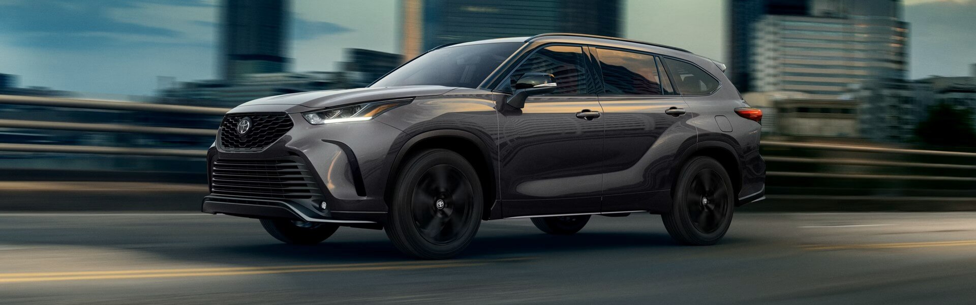 2026 Toyota Highlander driving on a city overpass Banner