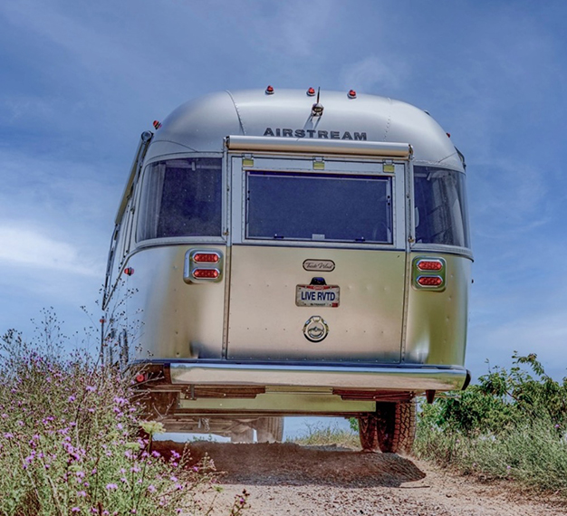 Airstream trailer seen from the rear driving through a trail