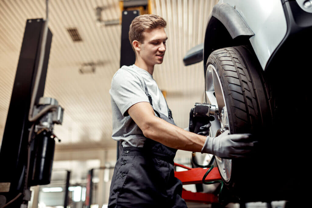 An Auto Mechanic Changing A Tire - Feature Image