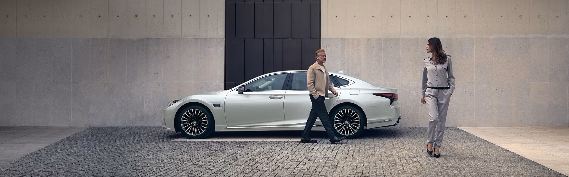 Banner of 2025 Lexus LS Hybrid luxury sedan parked in front of a modern, minimalist concrete building