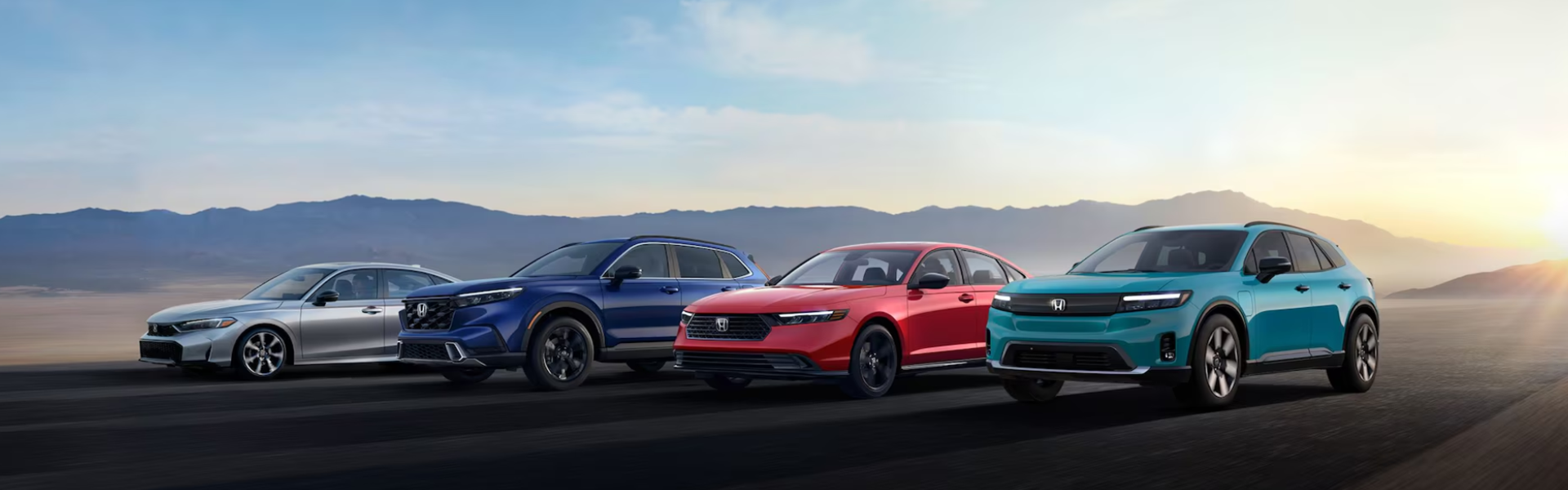 Lineup of Electric Honda vehicles set against a scenic backdrop with mountains and a rising or setting sun