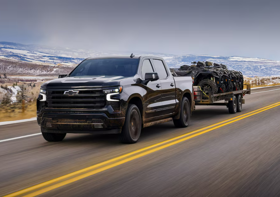 Used Chevrolet Silverado pickup truck towing a trailer loaded with off-road vehicles